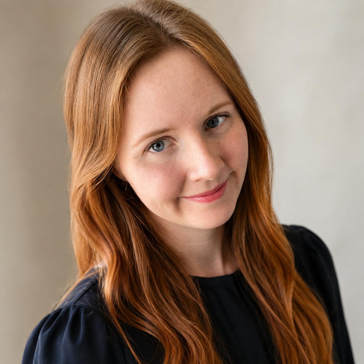 Woman with red hair facing camera with slight tilt of head.