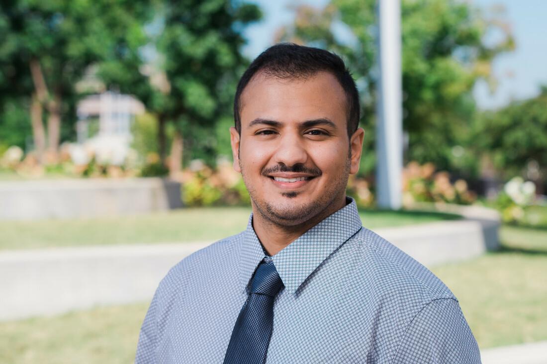 Man looking at camera in blue shirt and tie.