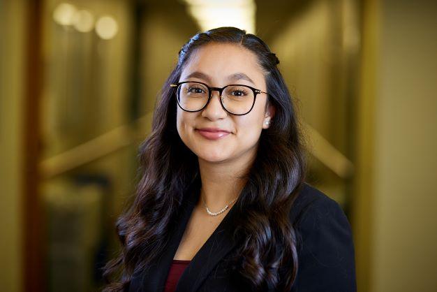 Woman with glasses and long brown hair smiling at camera.