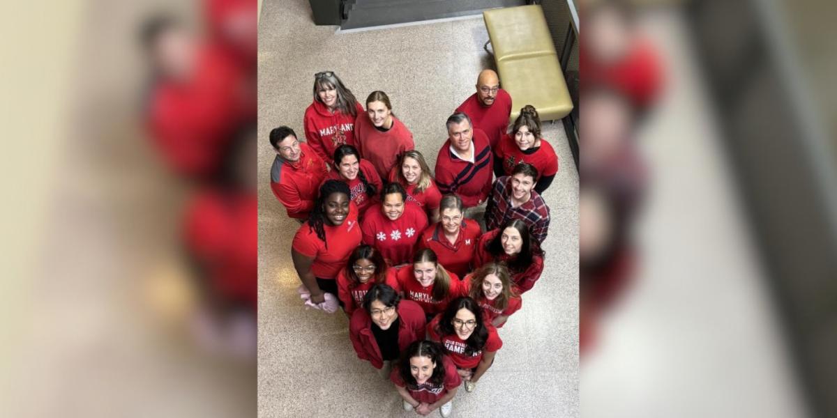 a group photo from above with the participants all wearing red and standing in the shape of a heart