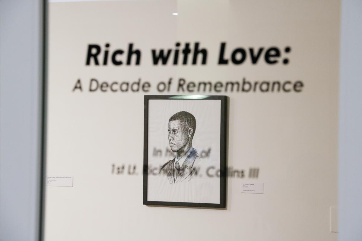 Exhibit title on glass door with portrait in the background of a Black man