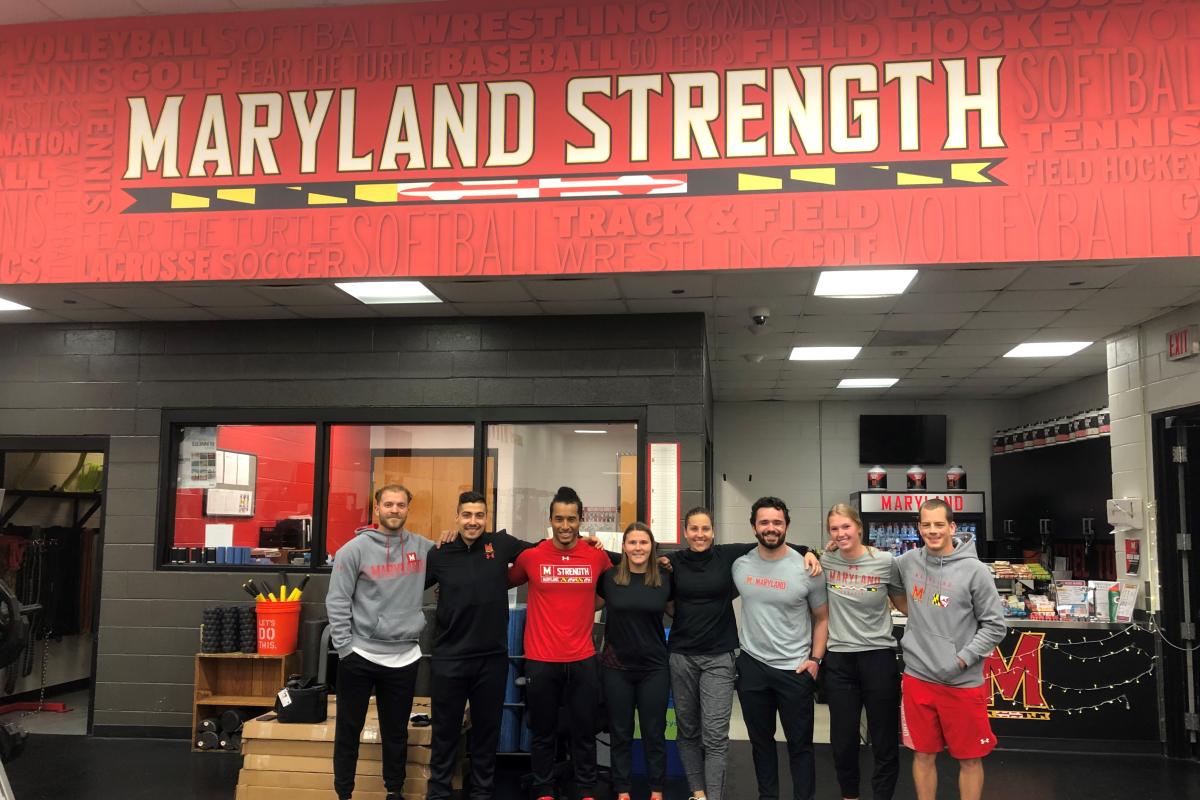 Students stand in a line under Maryland Strength sign on a red wall