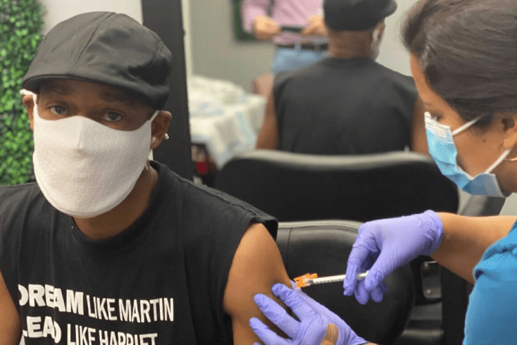 Black man receiving COVID vaccine in local barber shop