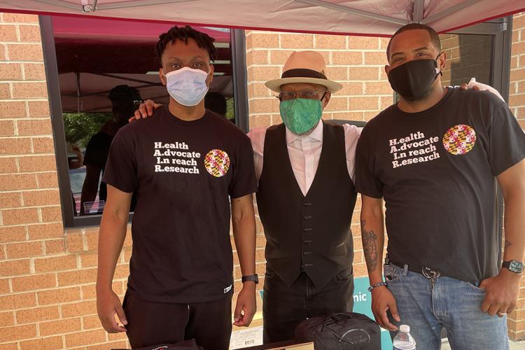 Stephen Thomas with two volunteers with the Health Advocates in Reach and Research program wearing masks at a COVID vaccine clinic at a beauty salon.