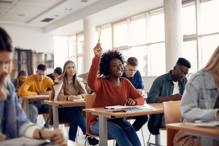 stock image of college classroom with student raising her hand