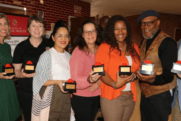 Group of Faculty hold awards and smile at camera
