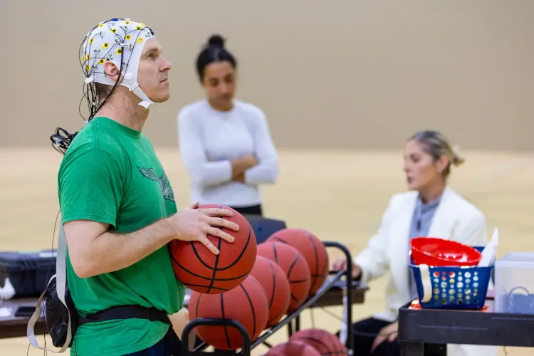 John Tucker lining up for a free throw, with an EEG cap on his head with wires to analyze brain activity