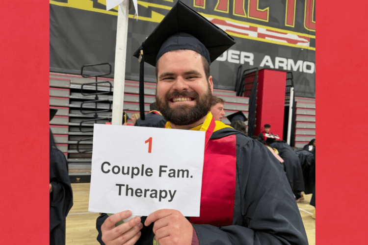 student in graduation dress smiles to camera