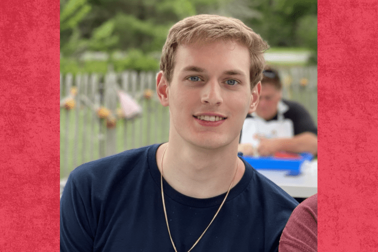 white male student wearing dark t-shirt smiles to camera