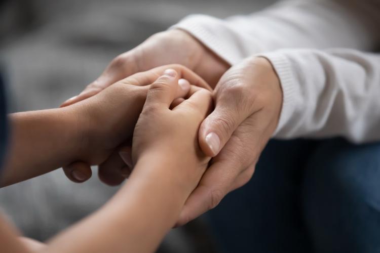adult hands hold child's hands