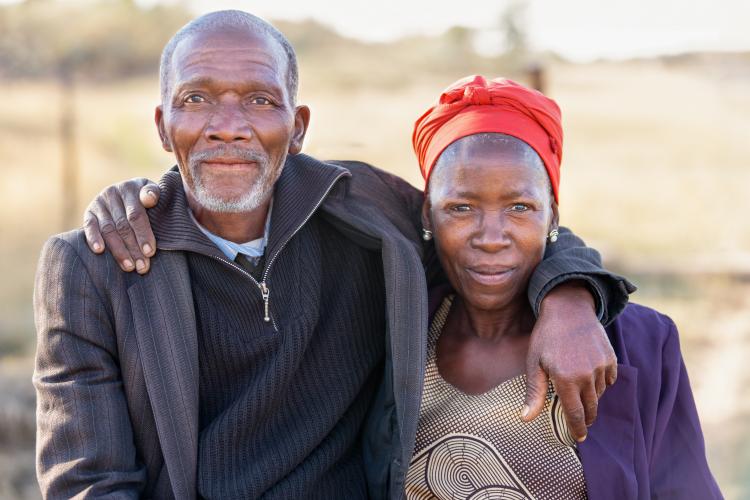 African couple look at the camera, with fields behind