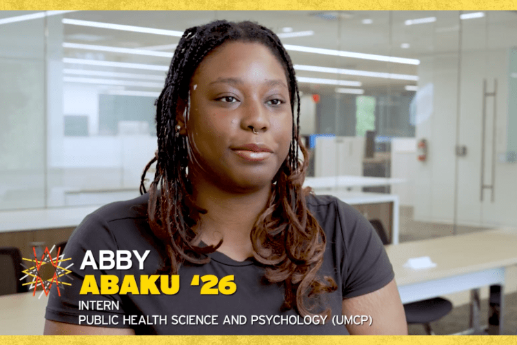 Black female student with long hair and black tshirt looks at camera, with her name on the bottom of the screen