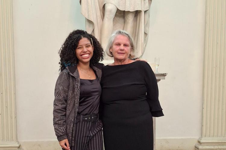 Brazilian student poses with American professor Kerry Tripp in Rio, standing in front of a marble statue. 