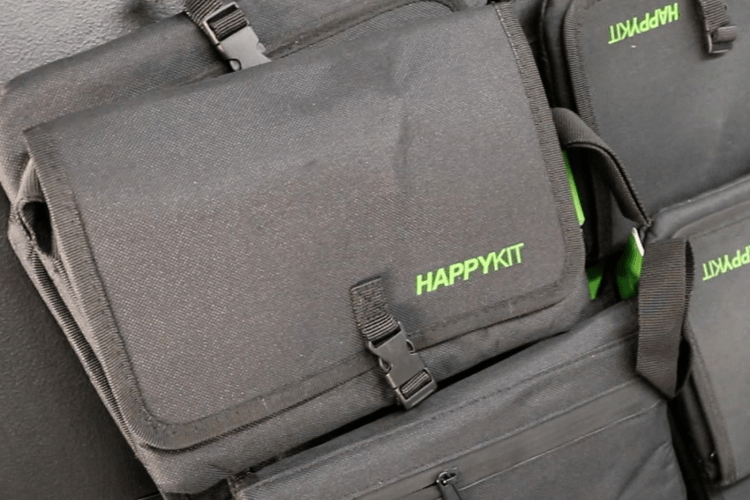 Black 'lock bags' with green words HAPPY KIT on front, stacked on a table