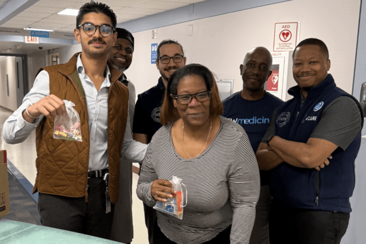Group of health workers stand in hospital corridor smiling to camera