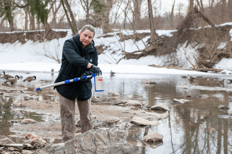grad student takes a water sample near the Potomac river sewage spill site