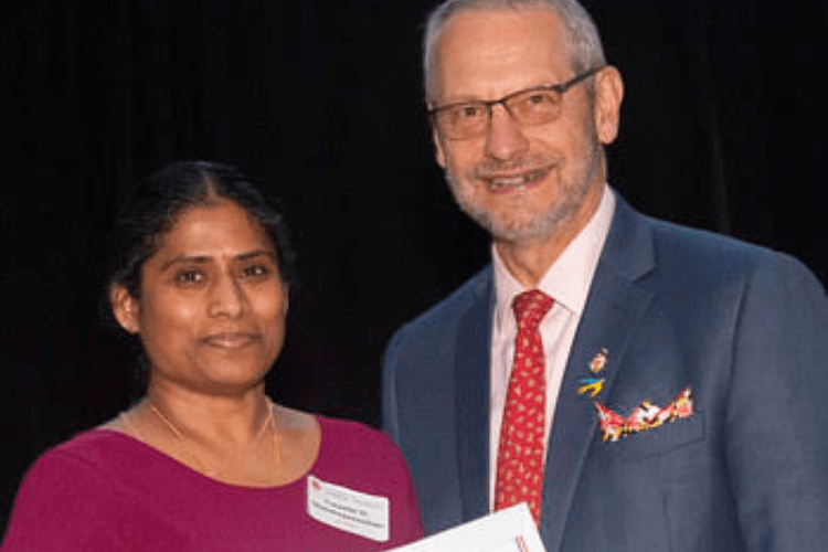 Graduate student stands with Dean holding a certificate, both smiling