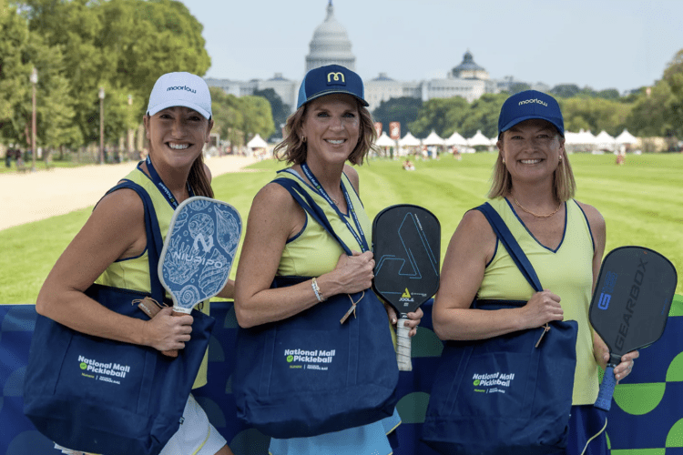Three women posing with pickleball paddles