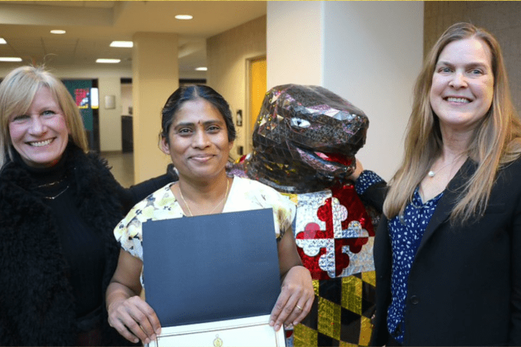 Two professors and one graduate student pose together in front of metallic terrapin mascot