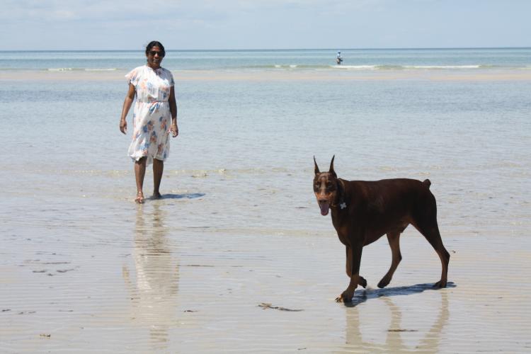 Graduate student standing with her dog at the beach on a sunny day