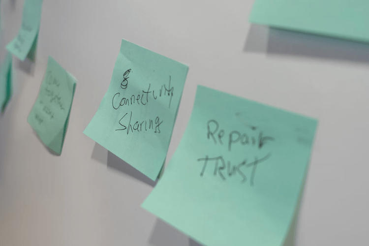 close up of a whiteboard with green sticky notes that read “Repair trust” and “connectivity sharing"