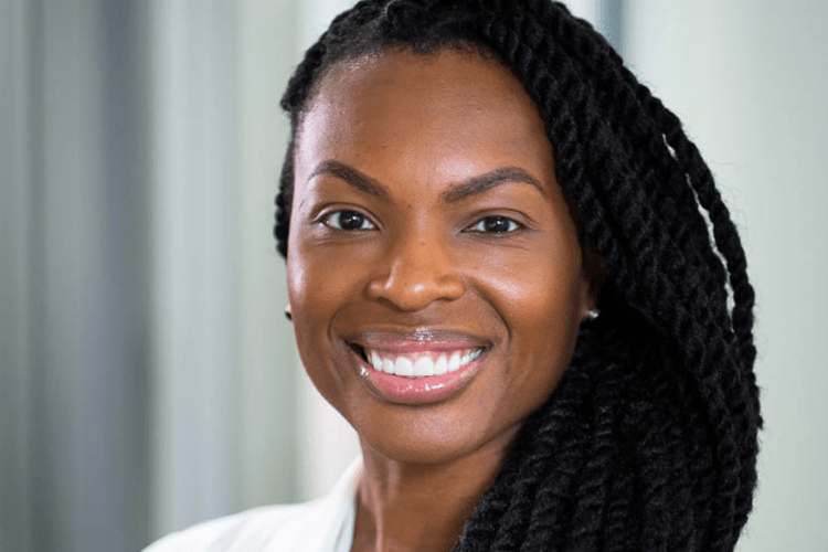 Headshot of a Black woman professor smiling to camera, wearing white shirt