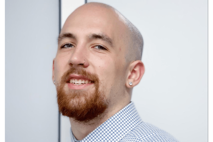 white man with goatee beard and bald head in a button down smiles to camera