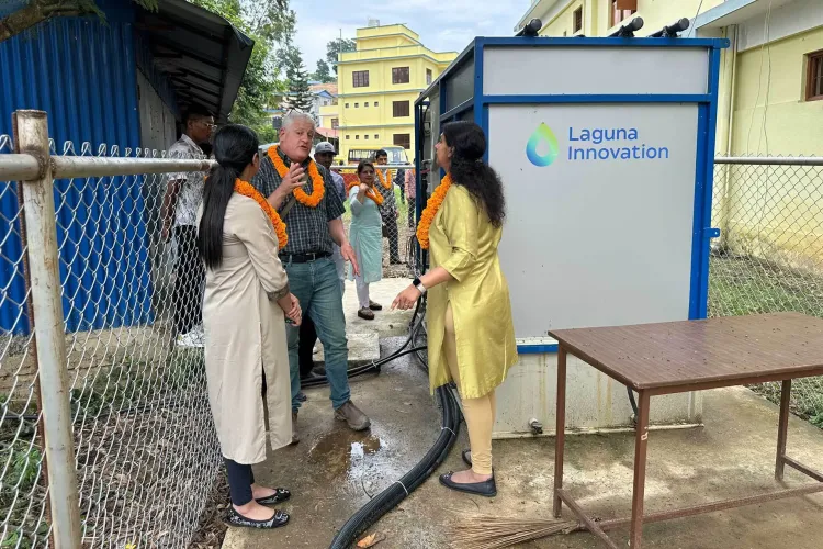 Asian women talking to a white man beside the Laguna Innovation machine that turns waste water into usable water