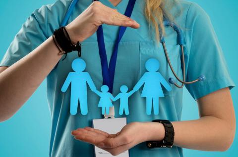 Nurse framing a paper family cutout with her hands