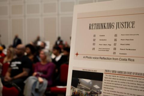foreground a posterboard about Costa Rica trip, in background an audience sits listening, in conference room