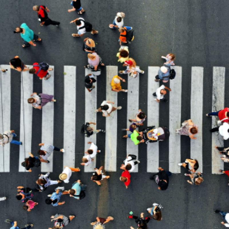 Aerial. People crowd motion through the pedestrian crosswalk.