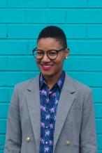 Erica Turner wearing glasses, patterned blue blouse and grey blazer.