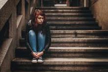 Sad young woman sitting on set of stairs