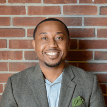 Black man with short hair smiling in a business suit