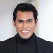 David Uriona wears black turtleneck shirt and suit. He has Dark hair and smiles