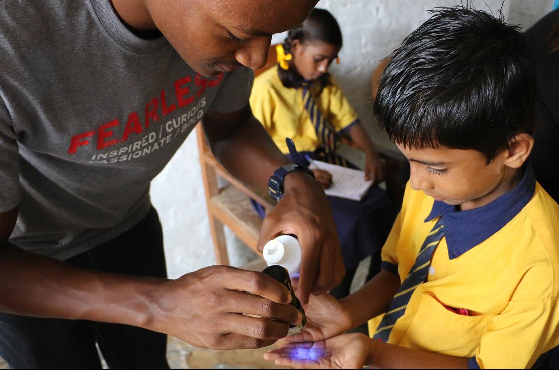 Global Health Initiative student participating in hand-washing activity with Indian children