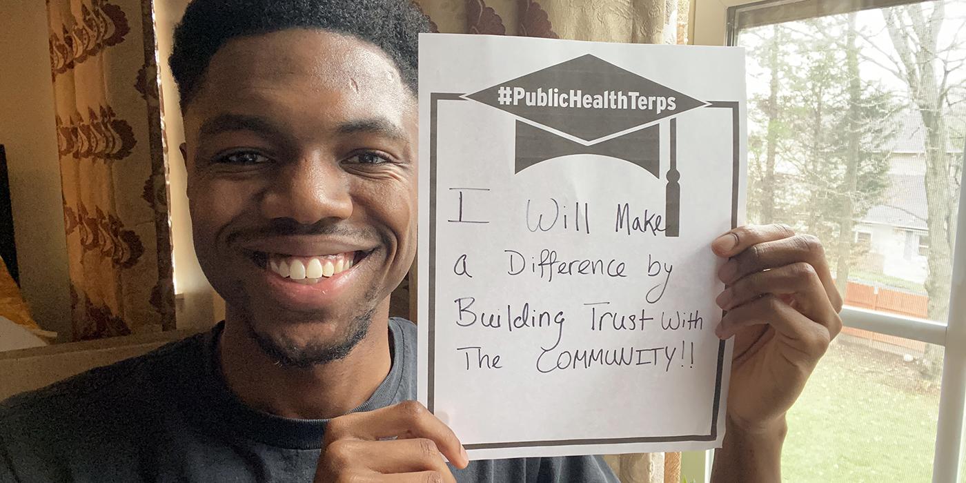 Nwabuisi Chinedu BS '20 holding sign that says "I will make a difference by building trust with the community."