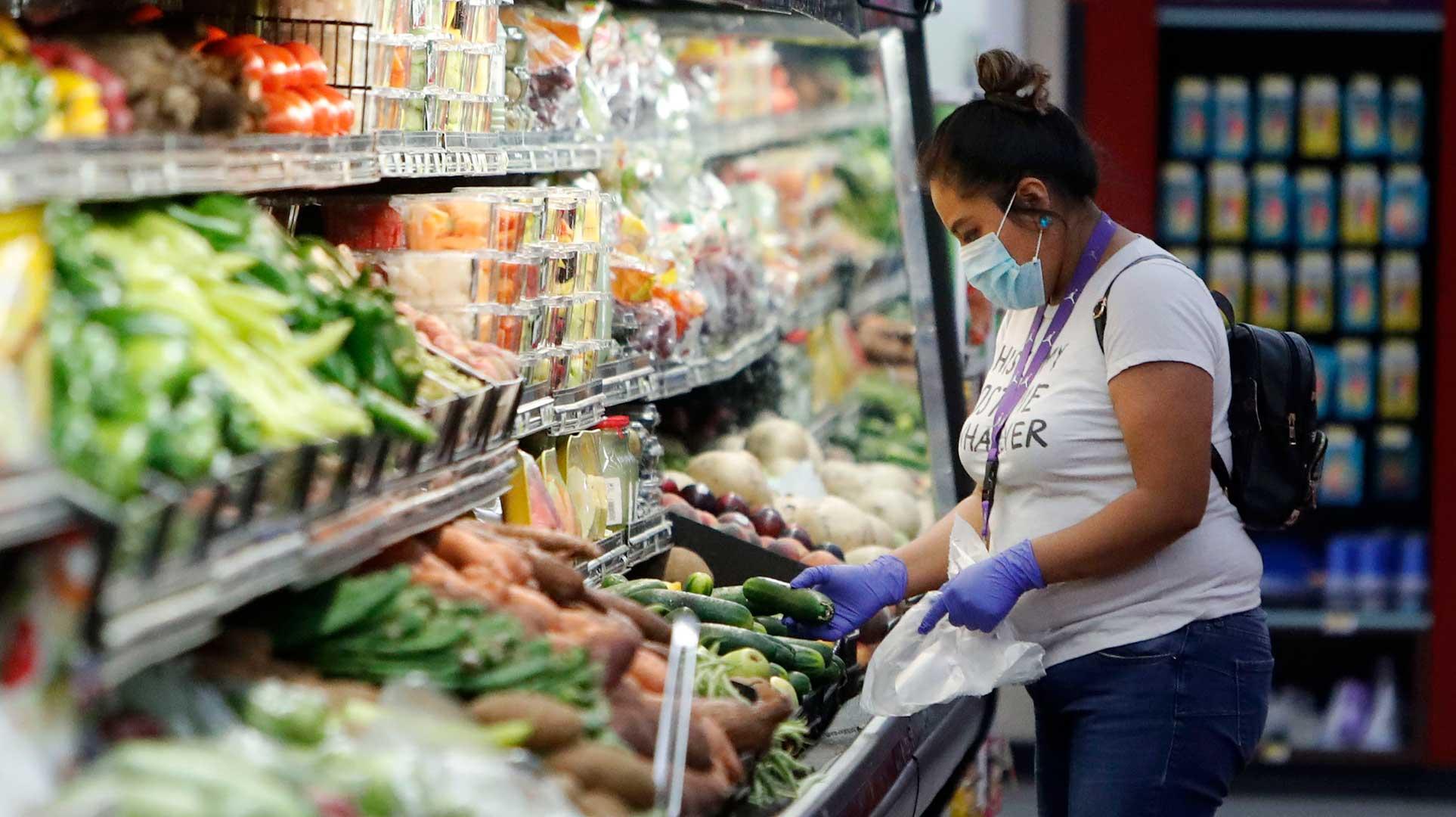 Woman shopping in grocery store wearing mask and gloves