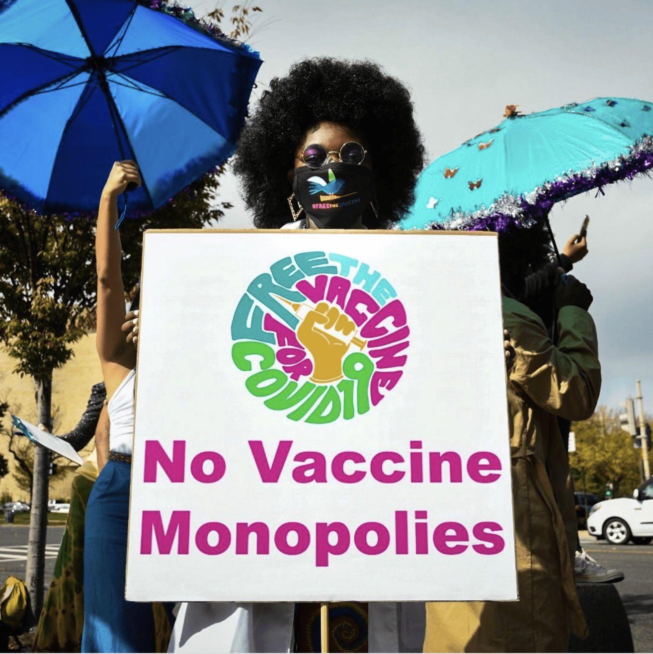 Black woman holds sign reading no vaccine monopolies