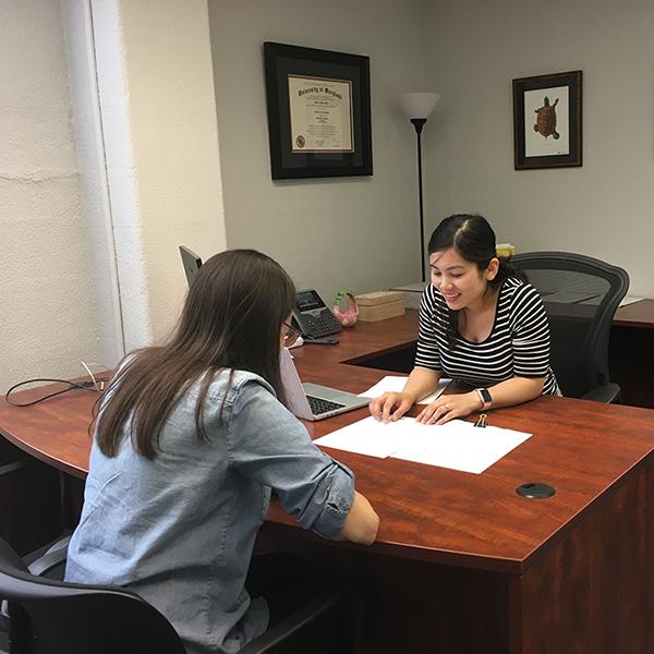 Public Health Science advisor sits at desk with a student