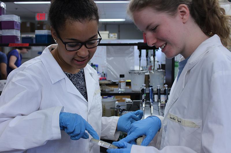 Students in lab coats observe a sample