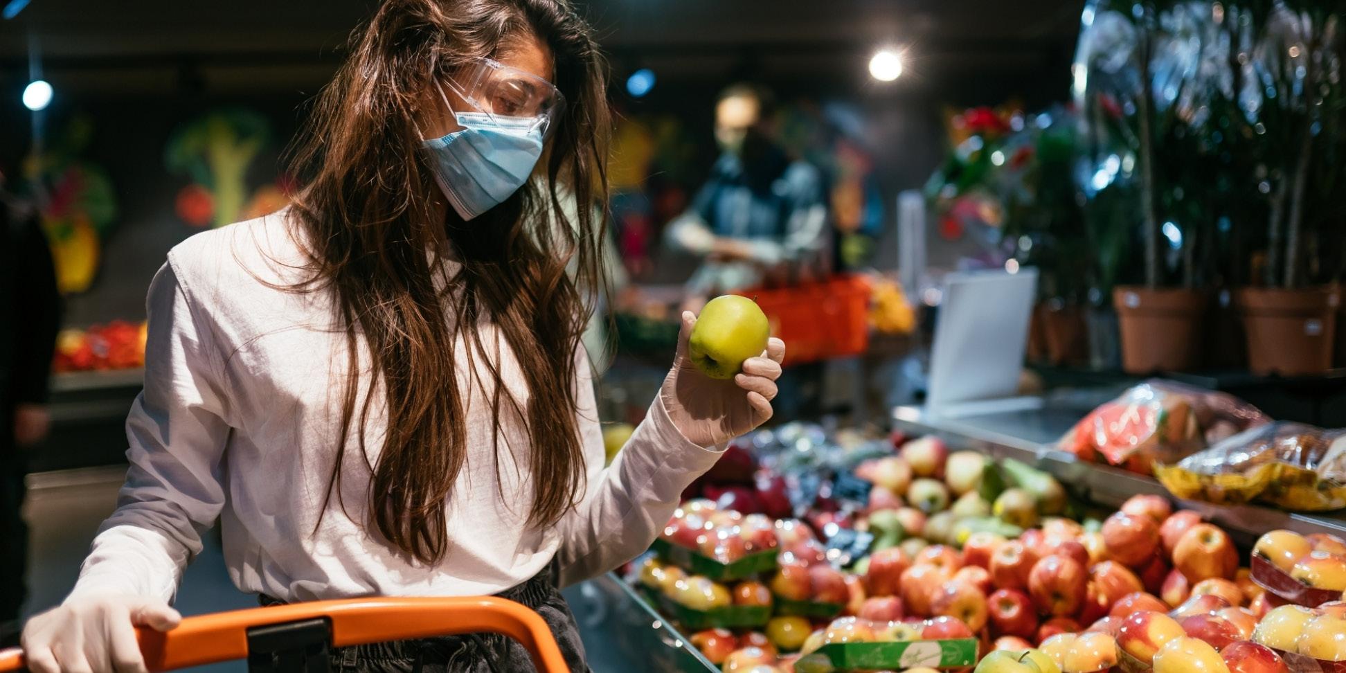 Woman wearing surgical mask while grocery shopping