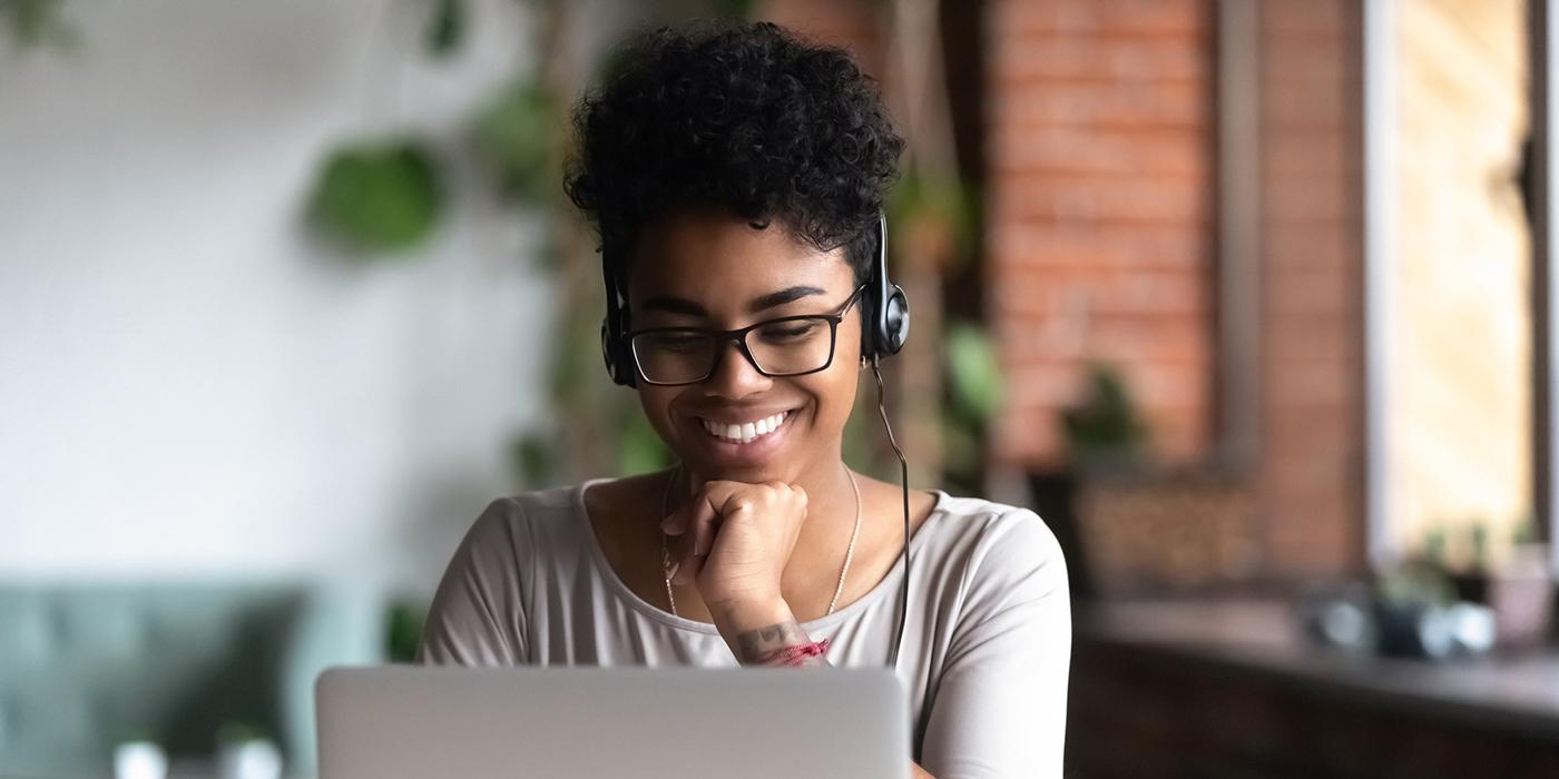 Happy student using headphones and a laptop