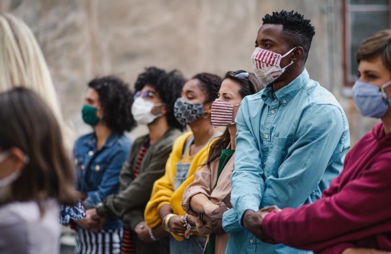 Group of activists protesting on streets, arms interlaced with masks on