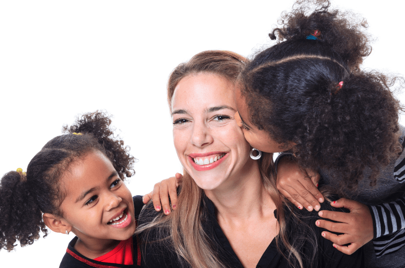 Two small children kissing their mother