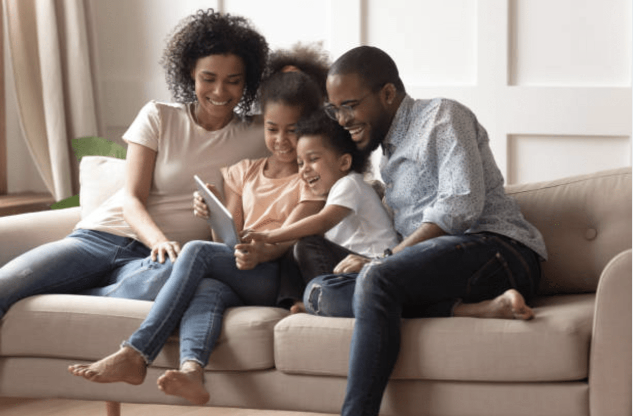 Black family Covid-19 sitting on a couch and looking at an iPad