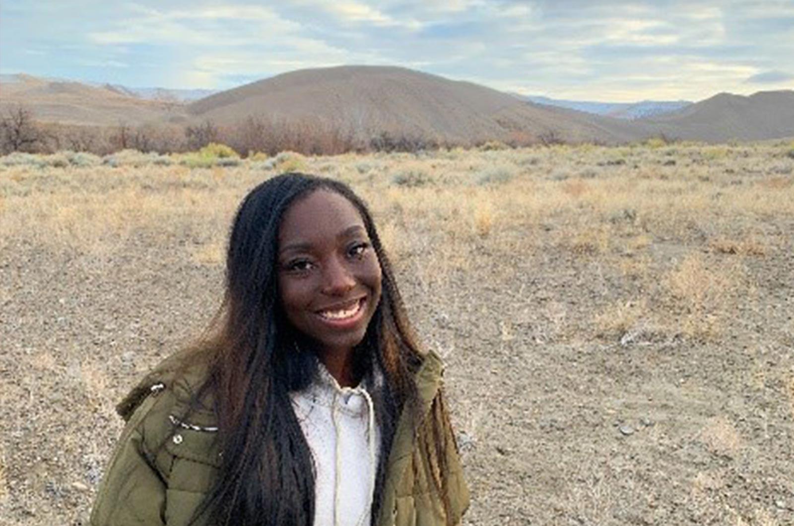 Student from the University of Maryland smiles at camera, posing in a dry landscape