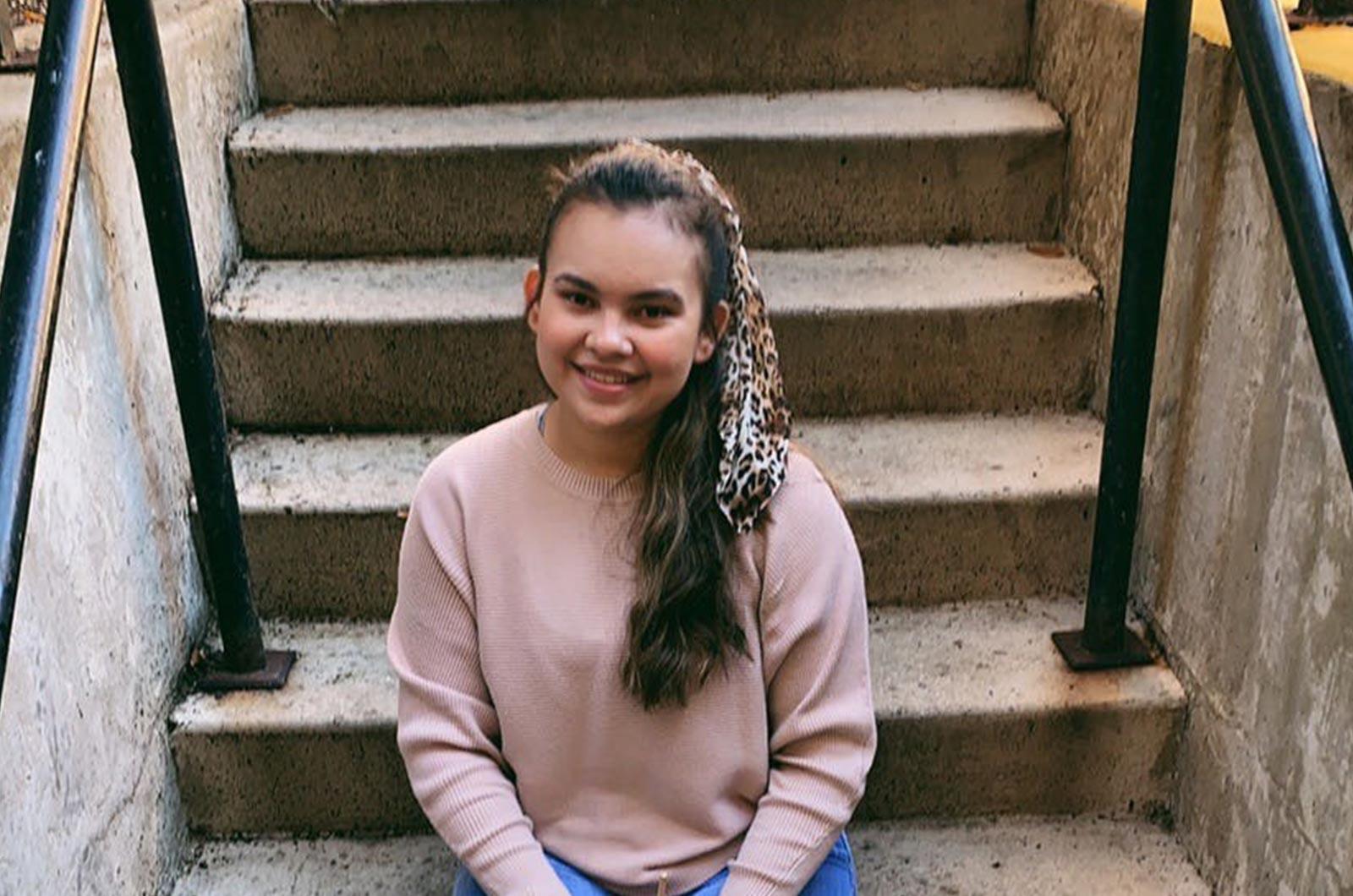 Student from the University of Maryland sitting on stairs smiling at camera