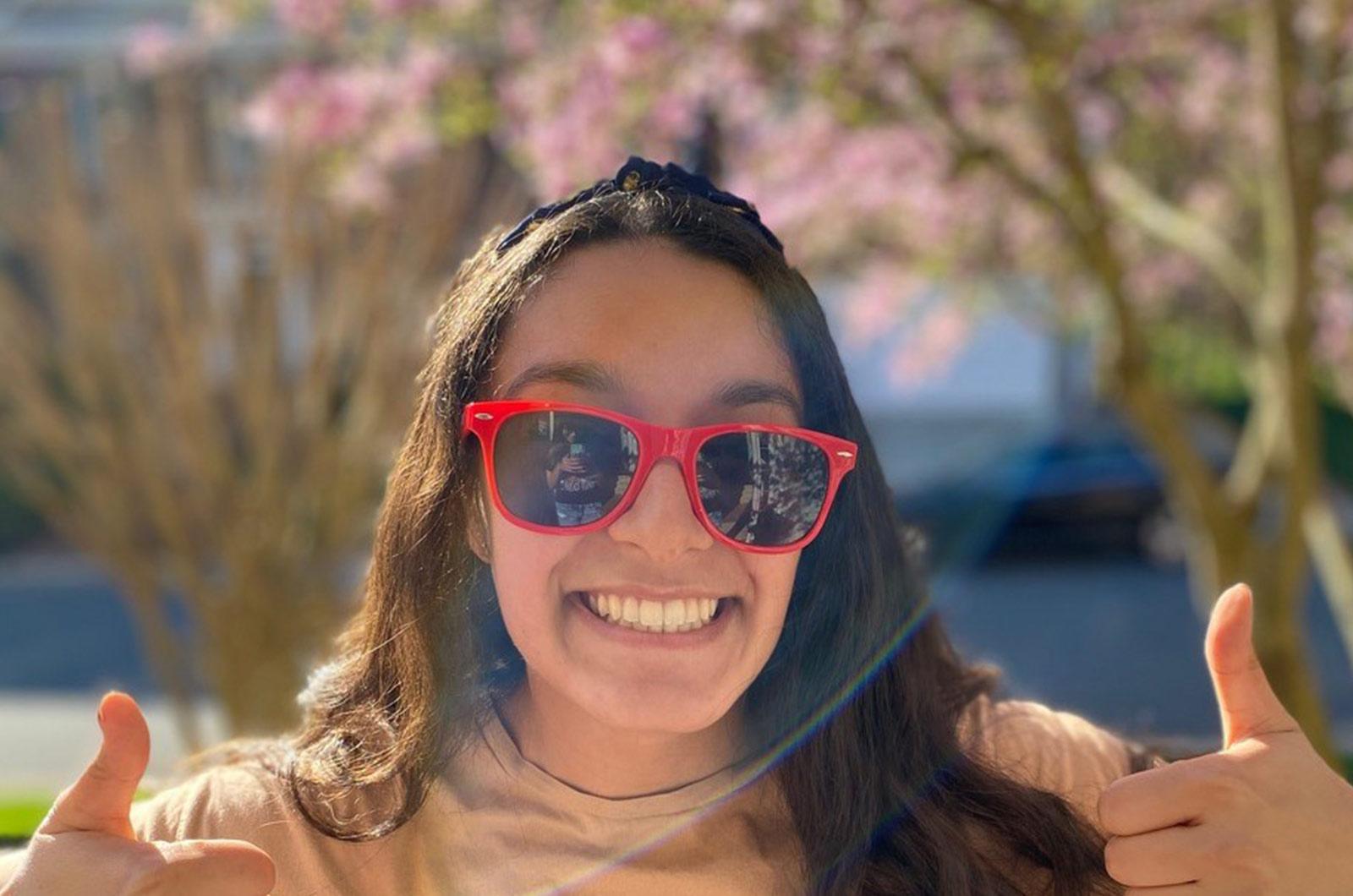 Student from the University of Maryland wearing sunglasses gives double thumbs up