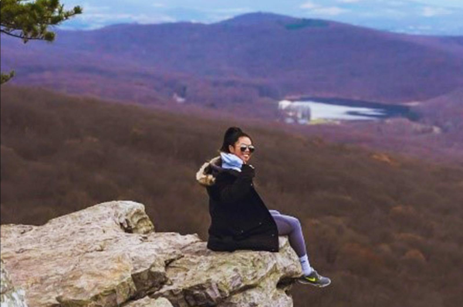 Student of the University of Maryland sitting on a big rock overlooking a valley
